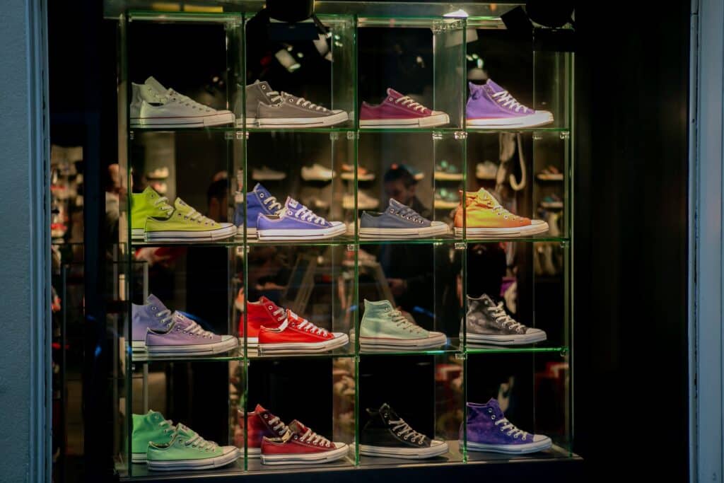 An assortment of multi-colored laced-up shoes on a glass shelf in a store window. Basket analysis can help boost product assortment planning. 