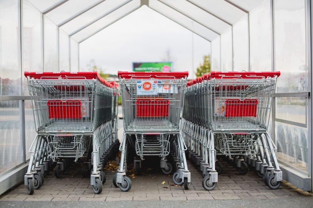 Three rows of shopping carts side by side. Market basket analysis in data mining allows retailers to know what basket items are frequently purchased together.